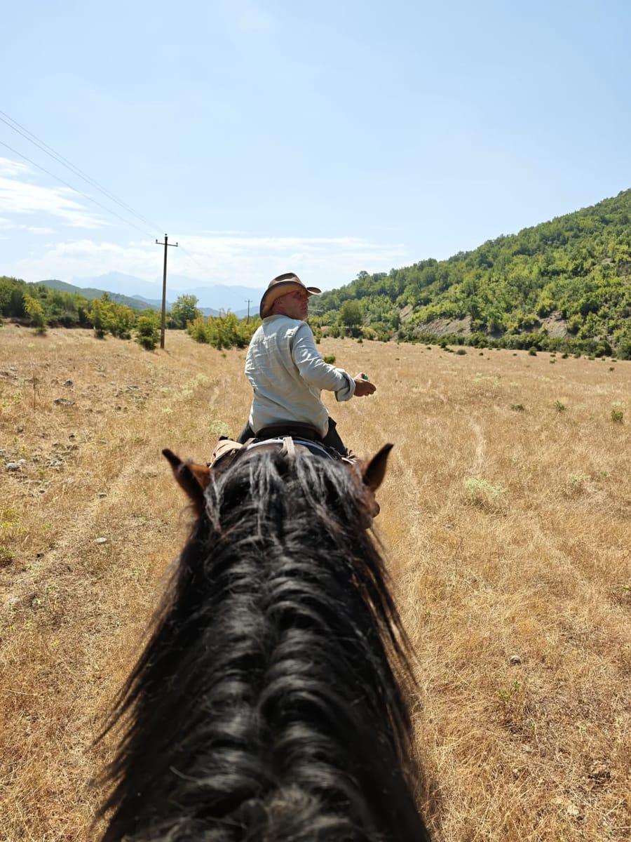 View between the horse’s ears of a guide riding ahead across a valley