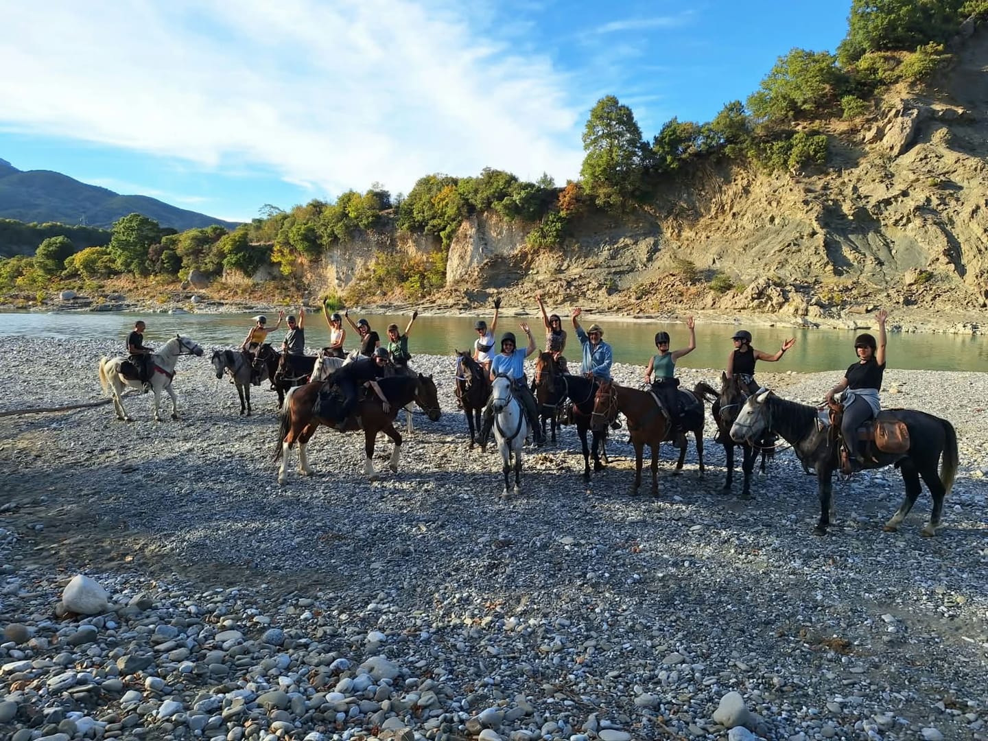 A group of riders on the gravel bank of a wide river